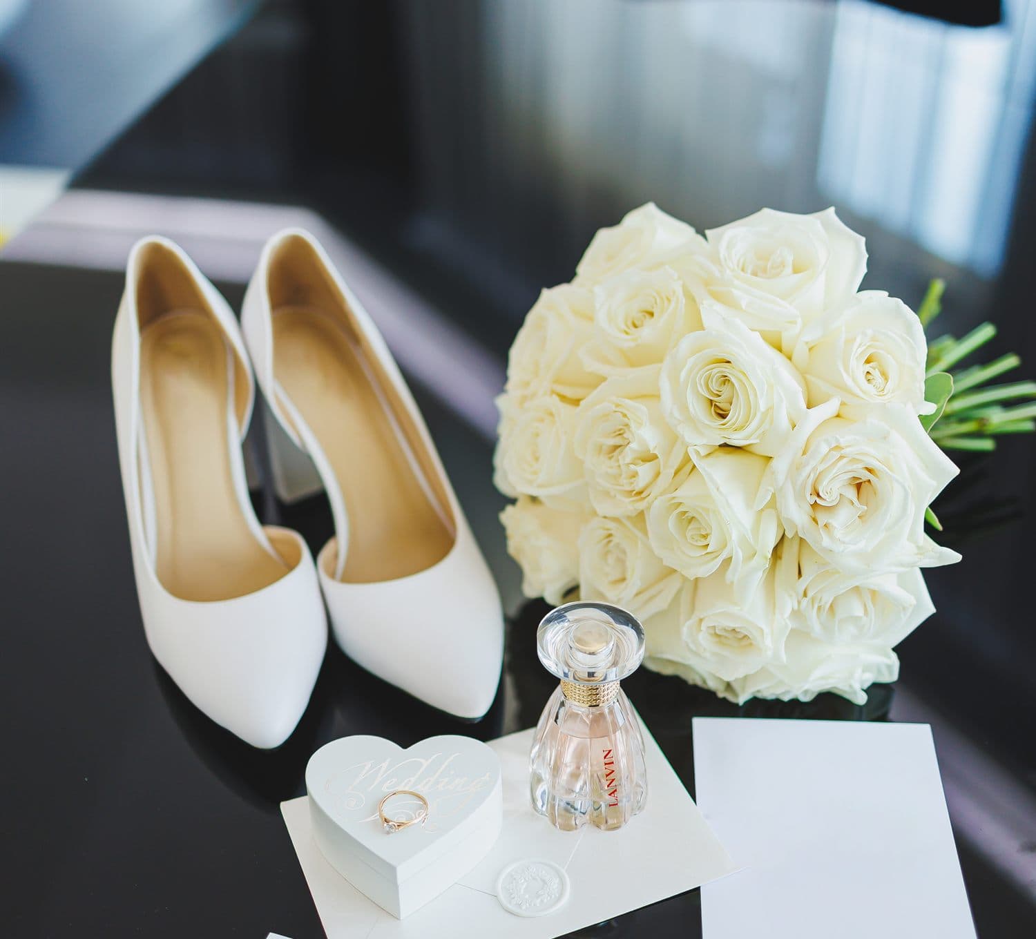 Zapatos de novia junto a un ramo de rosas blancas